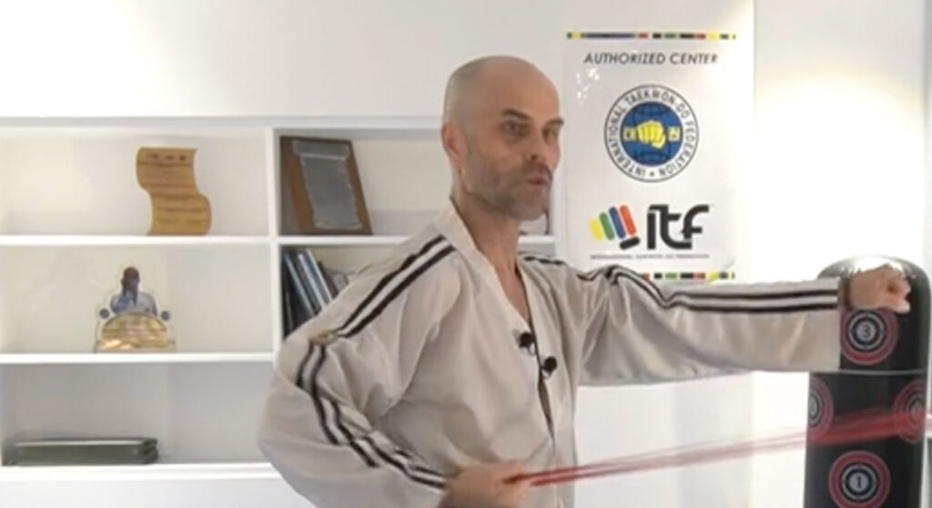 Master Mariusz showing the punching trajectory using resistance bands for demonstration.